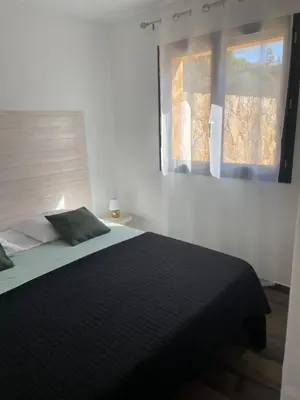 a bedroom with a black bed with a window at Villa Marilou avec petite piscine privée in Figari