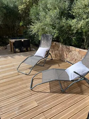 two chairs and a table on a wooden deck at Villa Marilou avec petite piscine privée in Figari