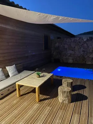 a wooden deck with a bench and a table and a pool at Villa Marilou avec petite piscine privée in Figari