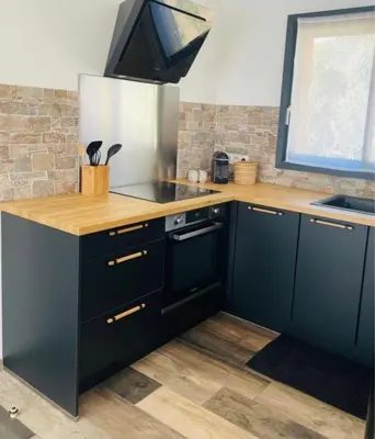 a kitchen with black cabinets and a wooden counter top at Villa Marilou avec petite piscine privée in Figari