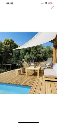 a white canopy over a wooden deck with a table and chairs at Villa Marilou avec petite piscine privée in Figari