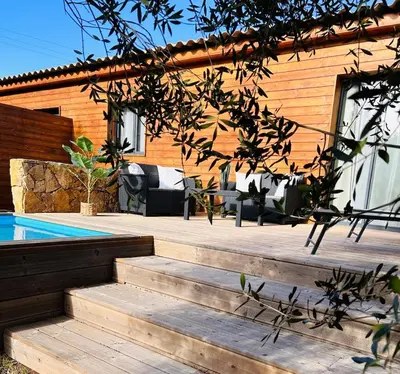 a house with a wooden staircase next to a swimming pool at Villa Carmen avec petite piscine privée in Figari