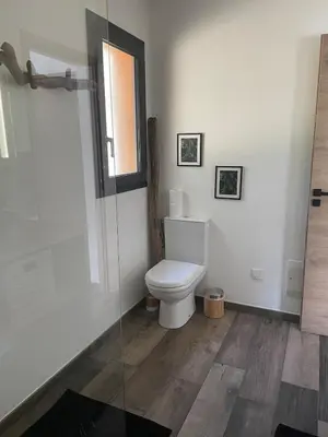 a white bathroom with a toilet and a window at Villa Carmen avec petite piscine privée in Figari