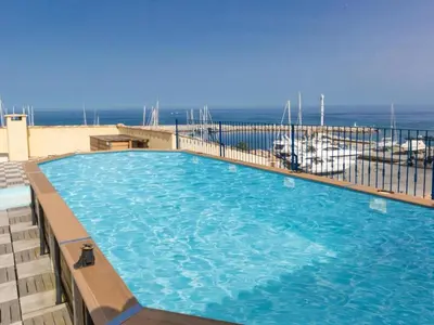 a large swimming pool on a balcony with the ocean in the background at Beautiful holiday home in Solenzara in Kamiesch