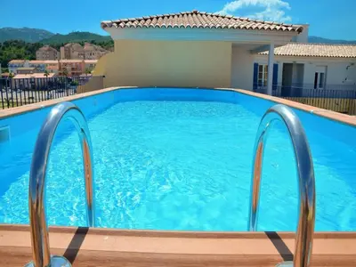 a swimming pool with blue water in front of a house at Beautiful holiday home in Solenzara in Kamiesch
