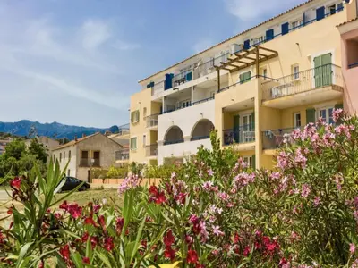 an apartment building with flowers in the foreground at Beautiful holiday home in Solenzara in Kamiesch