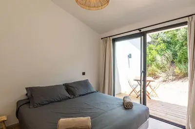 a bedroom with a bed and a large window at Maison Lucciana - Santa Giulia in Porto-Vecchio