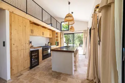 a kitchen with wooden cabinets and a large island at Maison Lucciana - Santa Giulia in Porto-Vecchio