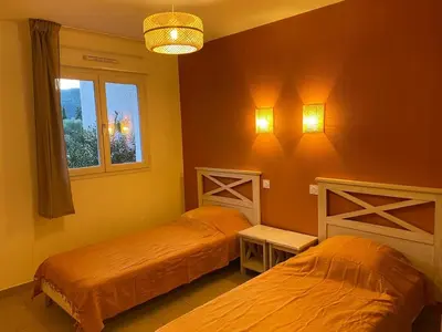 a bedroom with two beds and a window at Appartement 2 chambres - Rez-de-jardin - Avec piscine in Oletta