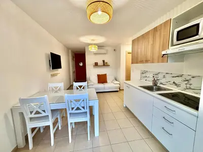 a kitchen and living room with a table and chairs at Appartement 2 chambres - Rez-de-jardin - Avec piscine in Oletta
