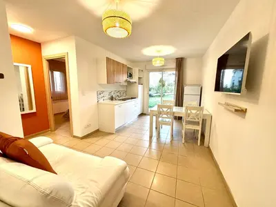a living room with a white couch and a table at Appartement 2 chambres - Rez-de-jardin - Avec piscine in Oletta