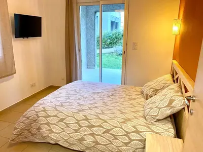 a bedroom with a bed and a sliding glass door at Appartement 2 chambres - Rez-de-jardin - Avec piscine in Oletta