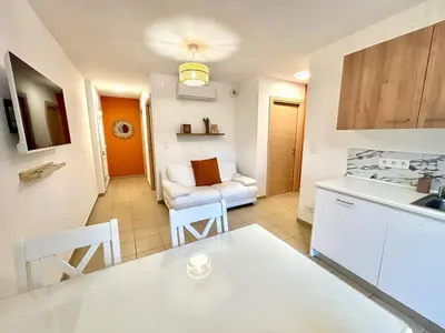a kitchen and living room with a table and a couch at Appartement 2 chambres - Rez-de-jardin - Avec piscine in Oletta