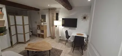 a living room with a table and a tv on the wall at Studio en centre ville a 2 minutes de la plage in Ajaccio
