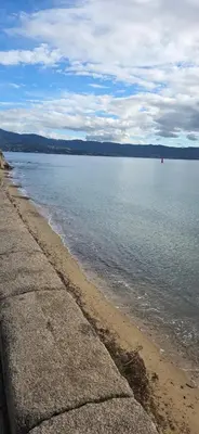 a view of a beach and the water with a red boat at Studio en centre ville a 2 minutes de la plage in Ajaccio