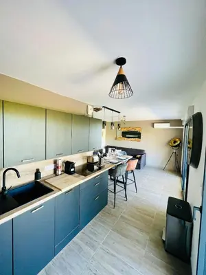 a kitchen with blue cabinets and a dining room at Alivu Immurtale - T3 design standing & confort, terrasse XXL in Propriano