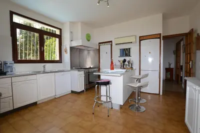 a kitchen with white cabinets and bar stools at Villa la Chiosella in Valle-di-Mezzana
