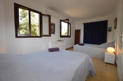 a bedroom with two beds and two windows at Villa la Chiosella in Valle-di-Mezzana