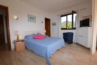 a bedroom with a bed and a chair and a television at Villa la Chiosella in Valle-di-Mezzana