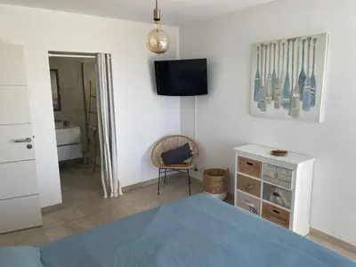 a bedroom with a bed and a tv and a chair at Villa Oletta, Saint Florent in Oletta