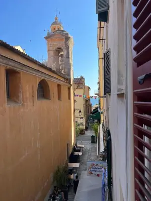 a narrow alley with a clock tower in the distance at Appartement centre historique Ajaccio in Ajaccio
