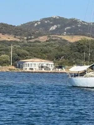 a boat in the water with a house in the background at Le Golfe in Figari
