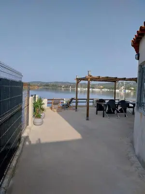 a patio with tables and chairs next to the water at Le Golfe in Figari