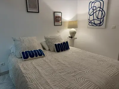 a bedroom with a large bed with blue pillows at Rez de villa, tout confort 4 pers parking Proche Ajaccio in Alata