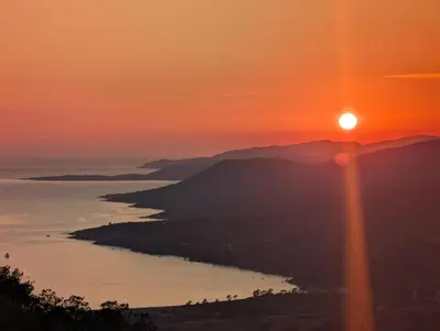 a sunset over a body of water with the sun setting at Casa Campana in Viggianello