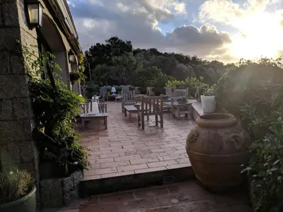 a patio with tables and chairs with the sun setting at Casa Campana in Viggianello