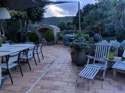 a patio with tables and chairs and a stone fireplace at Casa Campana in Viggianello
