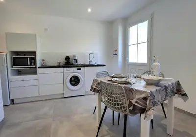 a kitchen with a table with chairs and a washing machine at Villa Canoe - Appartement 2 pièces in Santa-Maria-Poggio