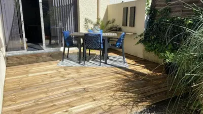a patio with a table and chairs on a wooden floor at Cozy cocoon 300m de la plage in Borgo