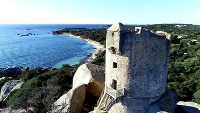 a building on top of a cliff next to the ocean at Villa avec Piscine in Pianottoli-Caldarello