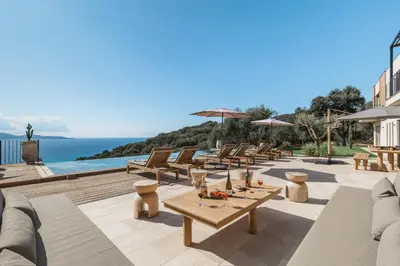 a patio with tables and chairs and the ocean at Magnifique villa 6 chambres avec piscine,Olmeto plage in Olmeto