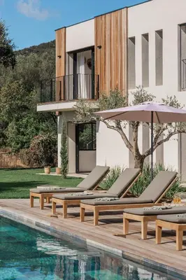 a pool with chairs and umbrellas next to a building at Magnifique villa 6 chambres avec piscine,Olmeto plage in Olmeto