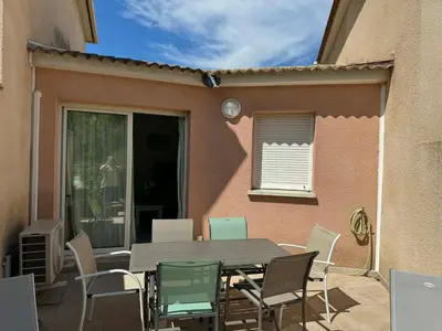 a table and chairs on a patio in front of a house at Mini villa Corse in Santa-Maria-Poggio
