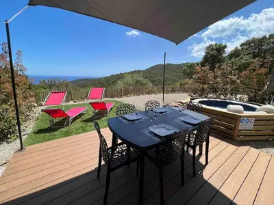 a table and chairs on a deck next to a hot tub at Charmant appartement en Rez-de-chaussée de VILLA - Classification 3 étoiles in Sari Solenzara