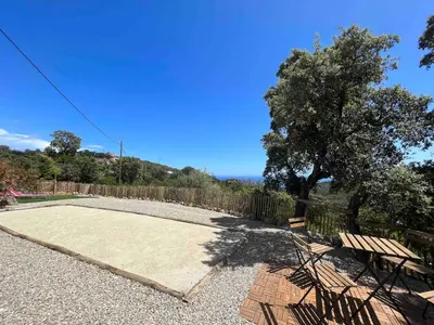 a patio with a table and a bench and a tree at Charmant appartement en Rez-de-chaussée de VILLA - Classification 3 étoiles in Sari Solenzara