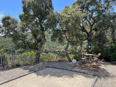 a patio with a table and a fence and trees at Charmant appartement en Rez-de-chaussée de VILLA - Classification 3 étoiles in Sari Solenzara