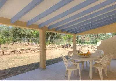 a table and chairs on a patio with a blue ceiling at A Filetta, Maquis & mer, dans un hameau de charme in Sartène