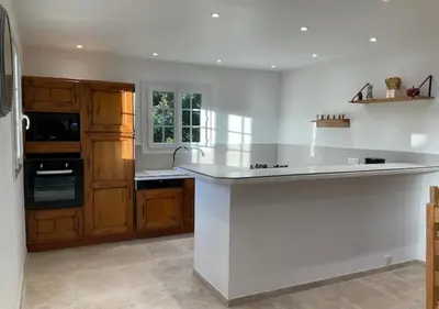 a kitchen with a white counter top and wooden cabinets at A Filetta, Maquis & mer, dans un hameau de charme in Sartène