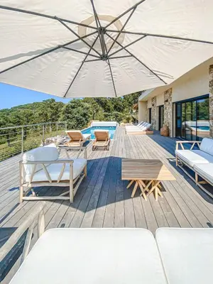 a wooden deck with chairs and an umbrella at Villa Margaux with private pool & sea view in Conca