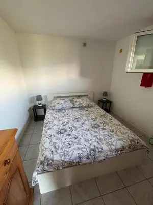 a bedroom with a bed with a white comforter at Rez de villa de 45 m2 Afa calme et fleuri in Afa
