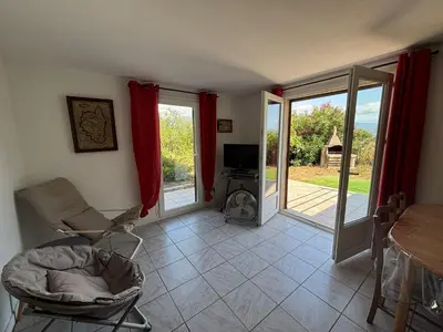 a living room with a chair and a table and sliding glass doors at Rez de villa de 45 m2 Afa calme et fleuri in Afa