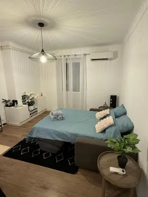 a bedroom with a blue bed and a table at Grand T2 Ajaccio - Proche port et transports in Ajaccio