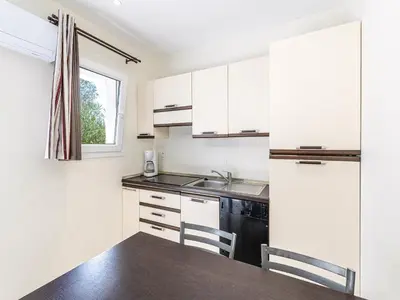 a kitchen with white cabinets and a sink and a table at Lisa Maria E N60 3P7 in Sari Solenzara