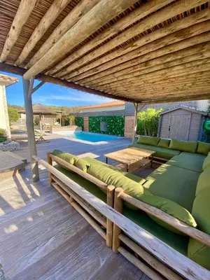 a patio with a wooden pergola and a couch at Belle villa avec piscine à Bonifacio in Bonifacio