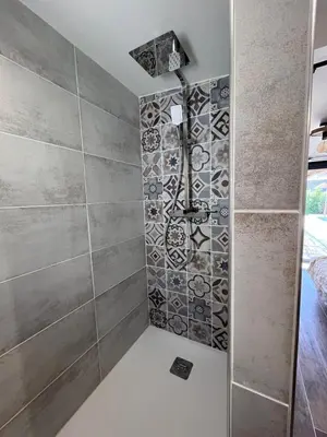 a shower in a bathroom with a tile wall at Belle villa avec piscine à Bonifacio in Bonifacio