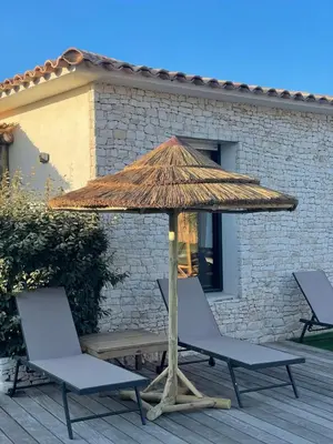 two chairs and a straw umbrella on a deck at Belle villa avec piscine à Bonifacio in Bonifacio